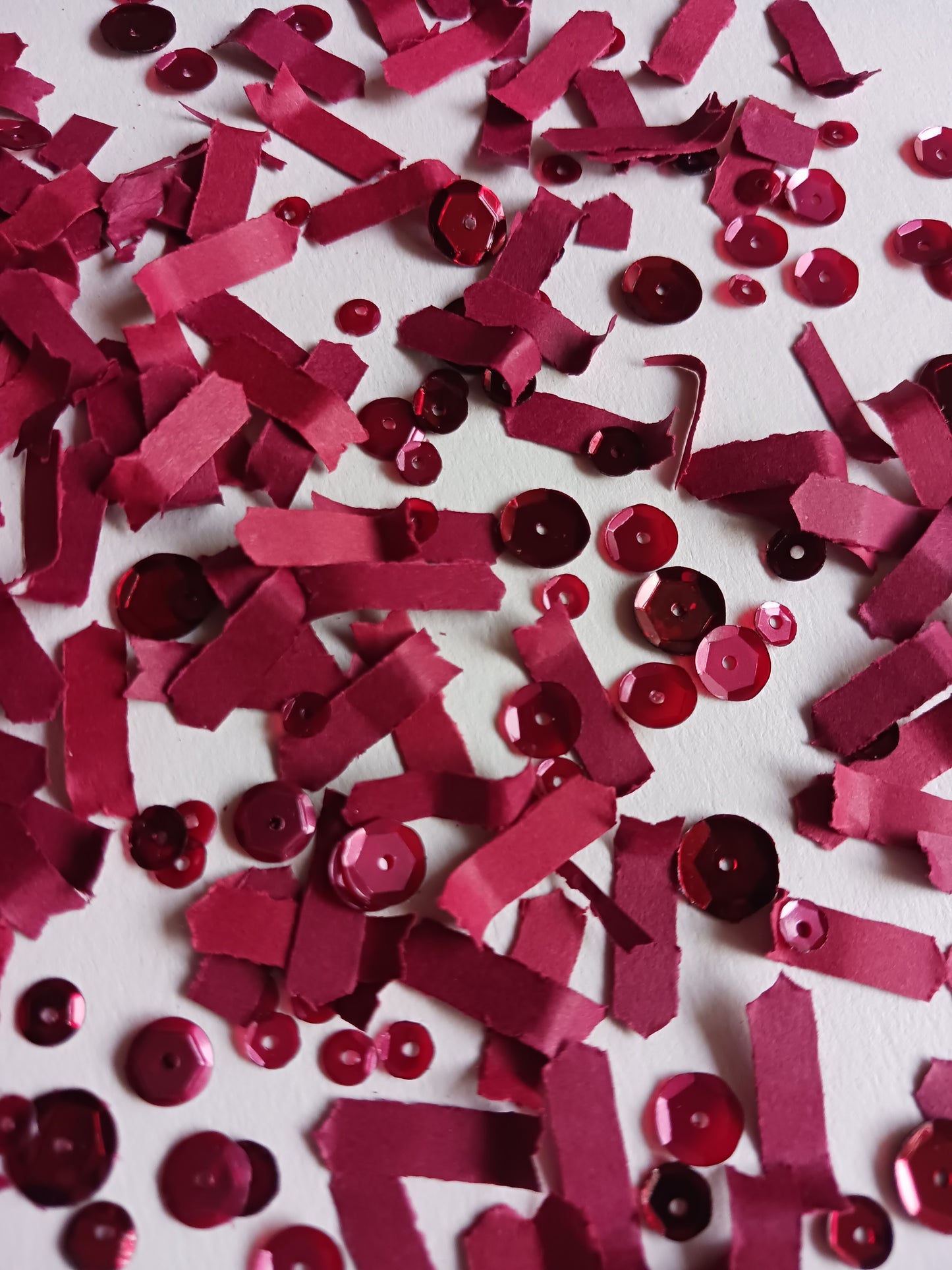 Red berry paper confetti and sequins on a white background.