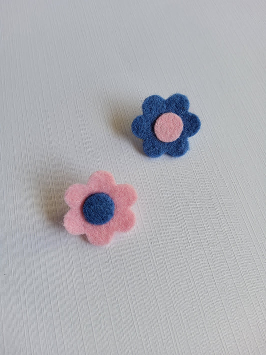 Two felt flowers, one blue and one pink, on a light gray background.