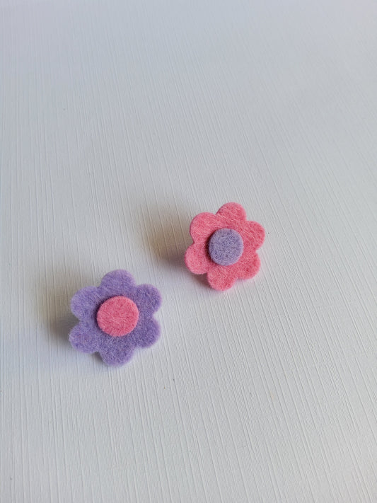 Two felt flowers, one pink and one purple, on a light gray background.