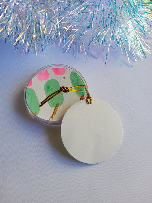 Pink, green, and gold accented abstract hand-painted round gift tags with gold cords showing the blank backing with an iridescent tinsel background