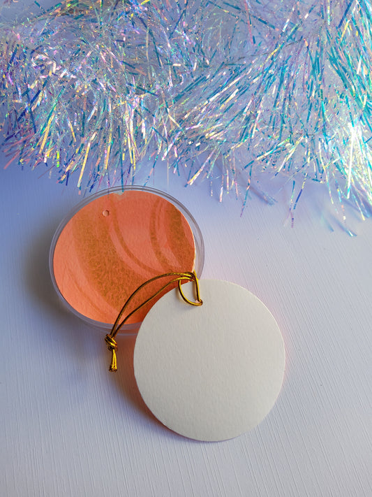 Gold and peachy coral abstract hand-painted round gift tags with gold cords and iridescent tinsel background