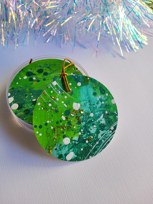 Green and gold glitter abstract hand-painted round gift tags with gold cords and iridescent tinsel background