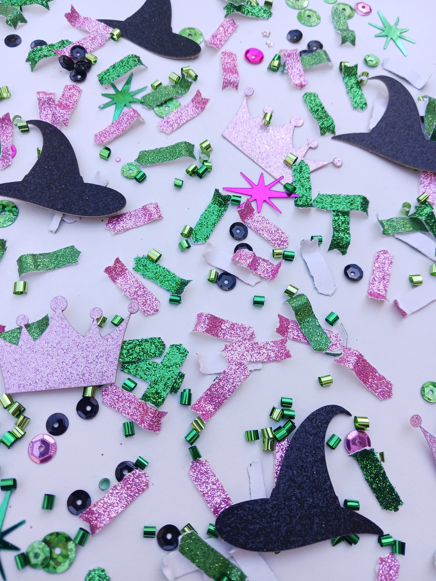 Green, pink and black witches party confetti on white background.