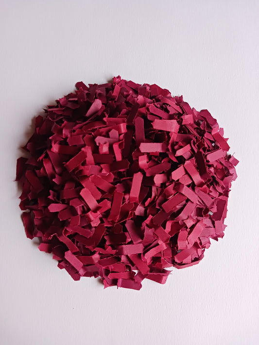Berry red confetti in a round pile on white background. 