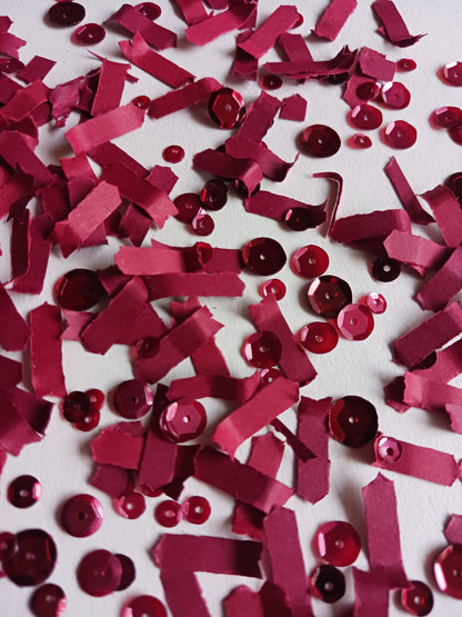 Red berry paper confetti and sequins on a white background. 