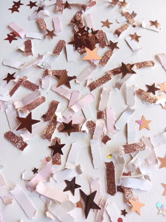 Rose gold star-shaped confetti in various colors on a white background