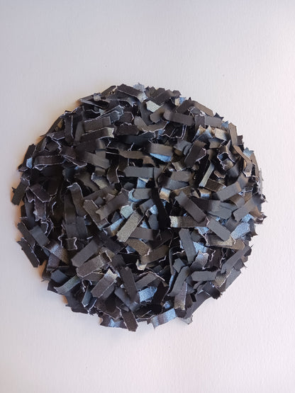 Heap of black paper confetti on white background. 