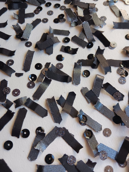 Scattered black confetti with black sequins on a white background. 