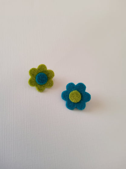 Two felt flowers, one blue and one green, on a white background.