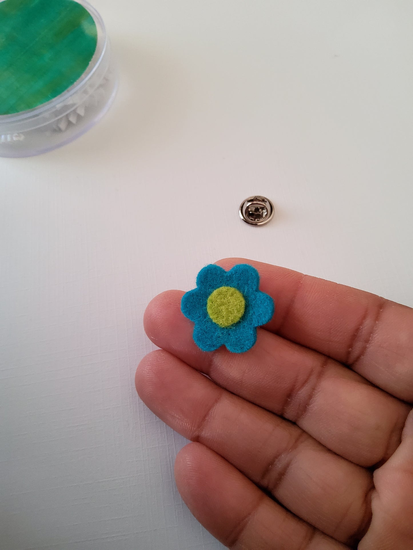 Hand holding a small blue flower-shaped object against a white background