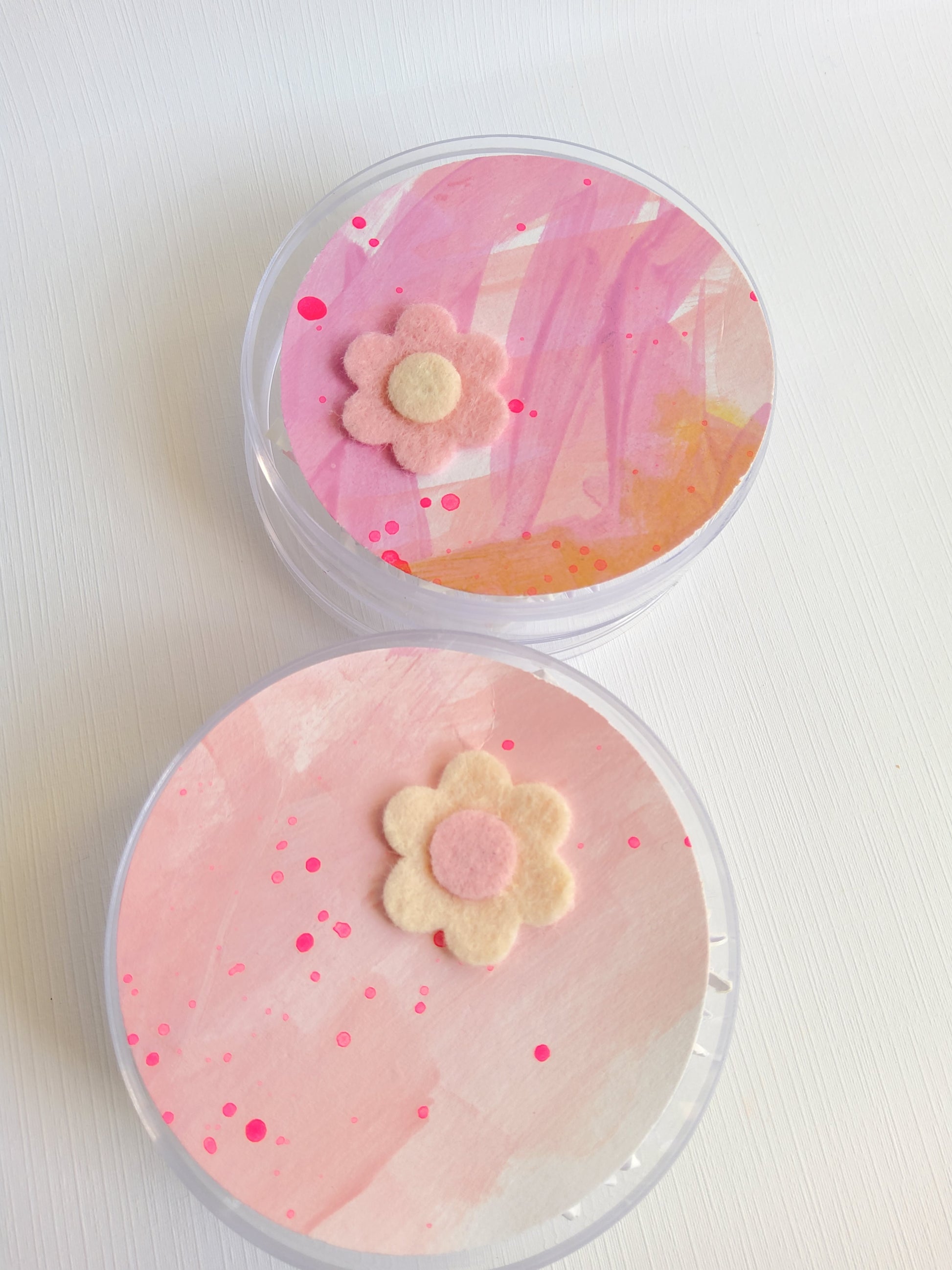 Two round containers with pink floral designs on a white background