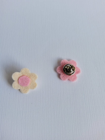 Two flower-shaped pins on a light textured background
