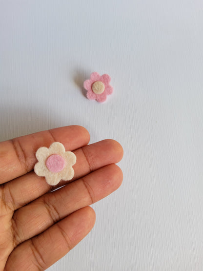 Small felt flower pins on a person's hand against a light background