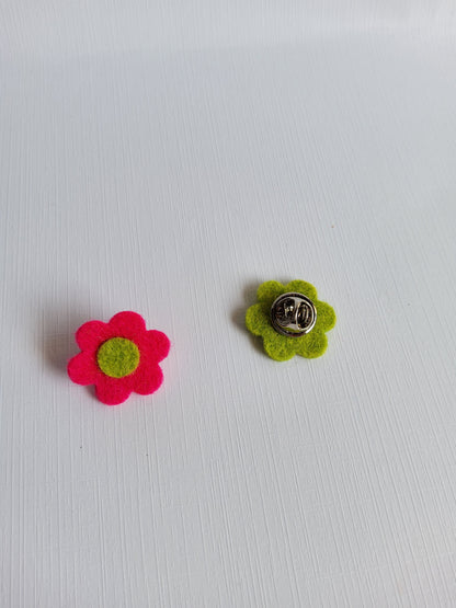 Two felt flower pins, one green and one pink, on a white background.