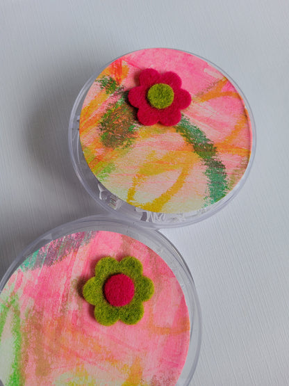 Two small round containers with colorful floral designs on a light gray background