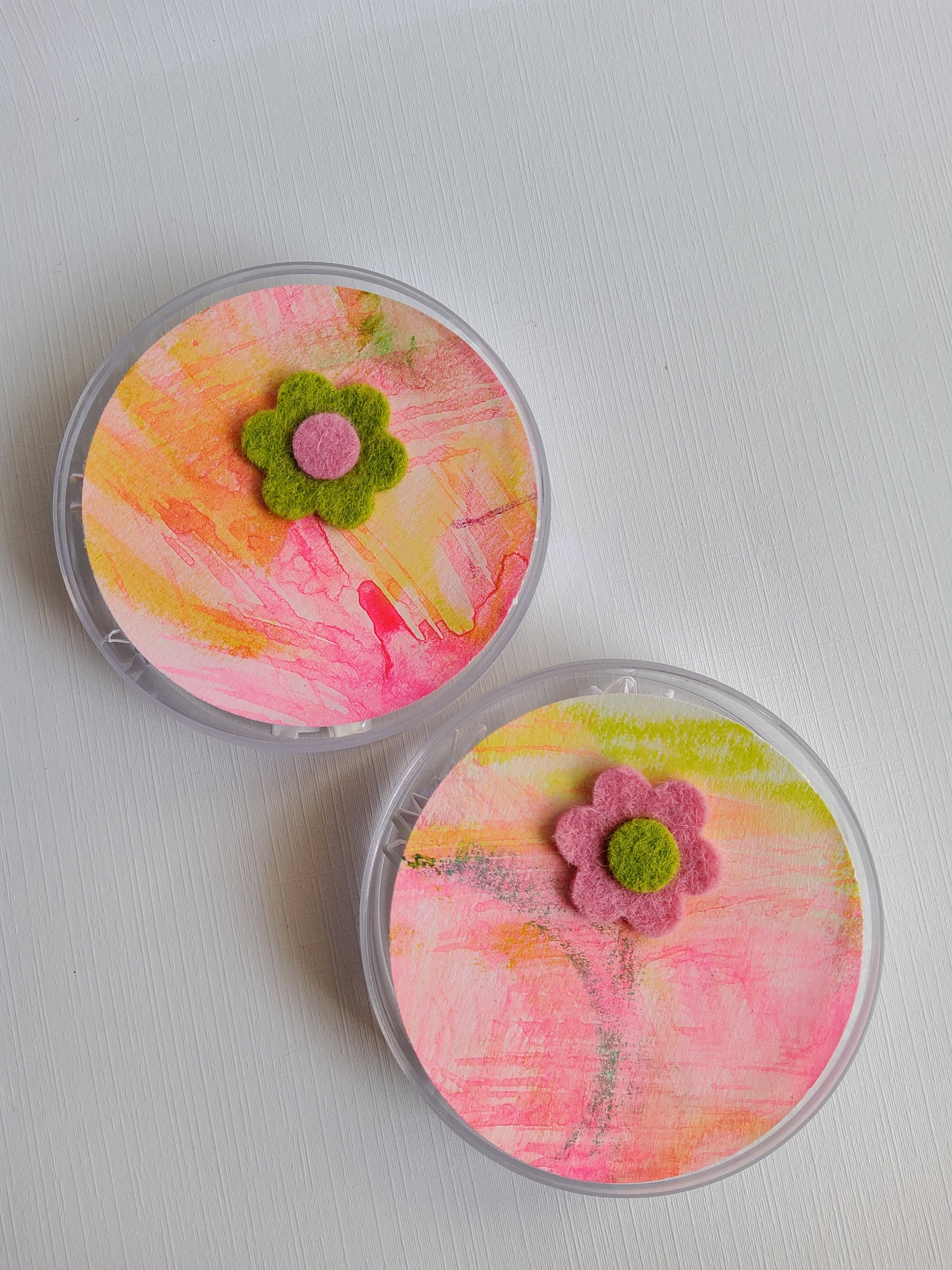 Two round containers with colorful designs and flower decorations on a white background