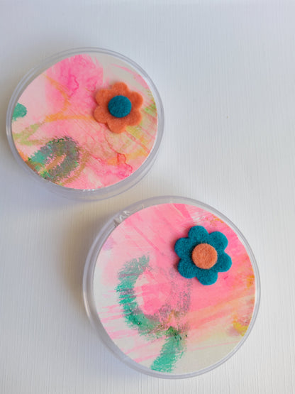 Two round containers with colorful floral designs on a white background