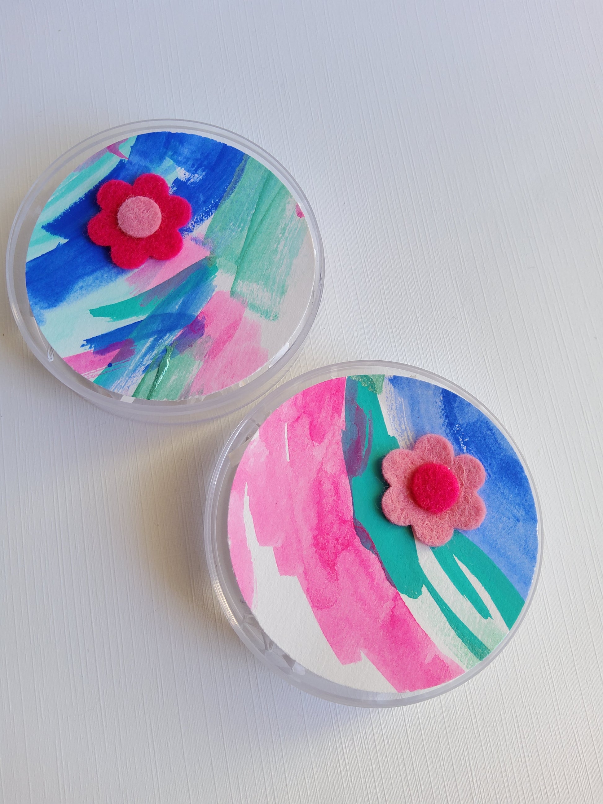 Two round containers with colorful floral designs on a white background