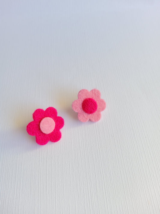 Two pink felt flower lapel pins on a textured white background