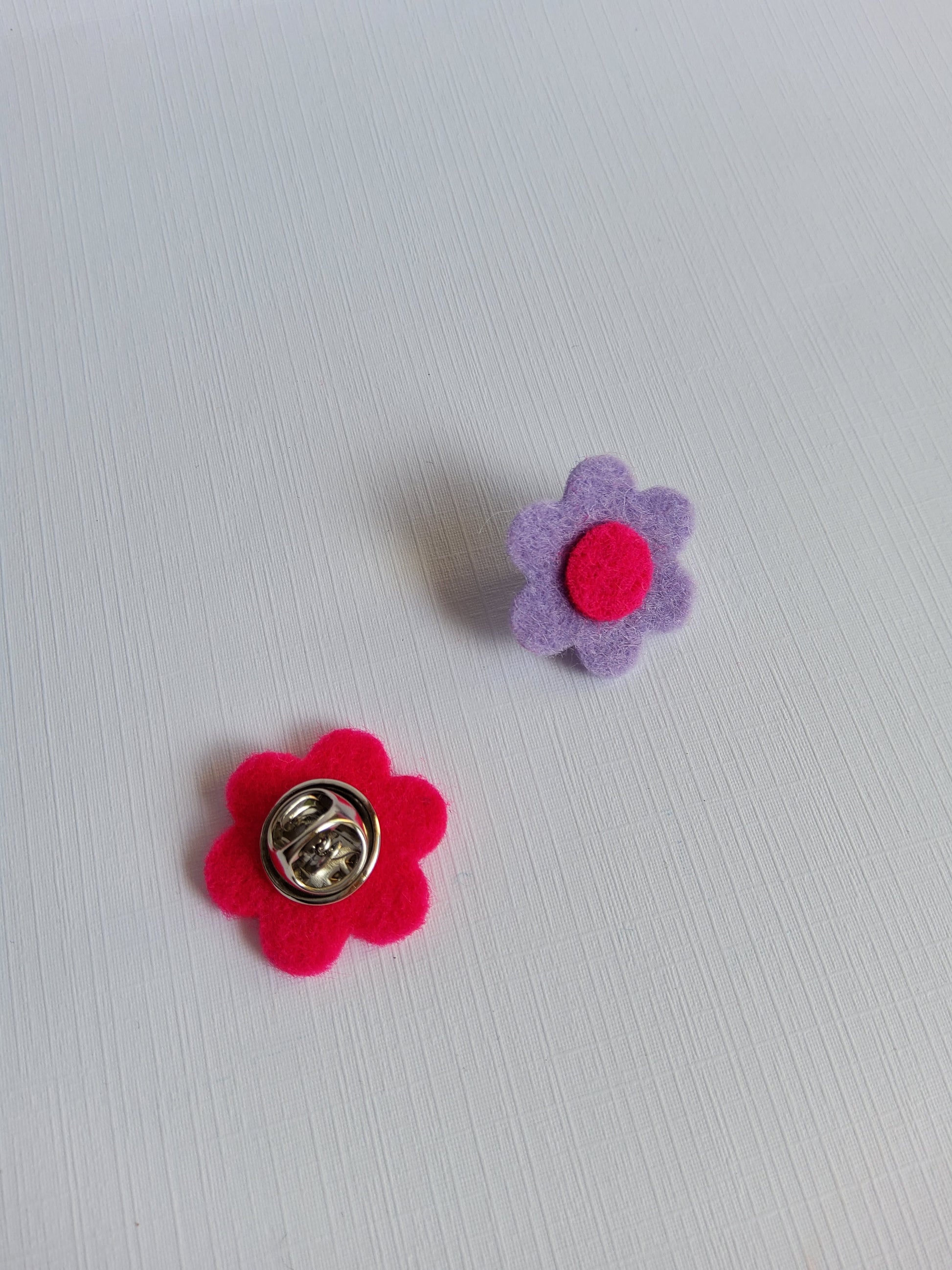Two flower-shaped pins on a light gray background