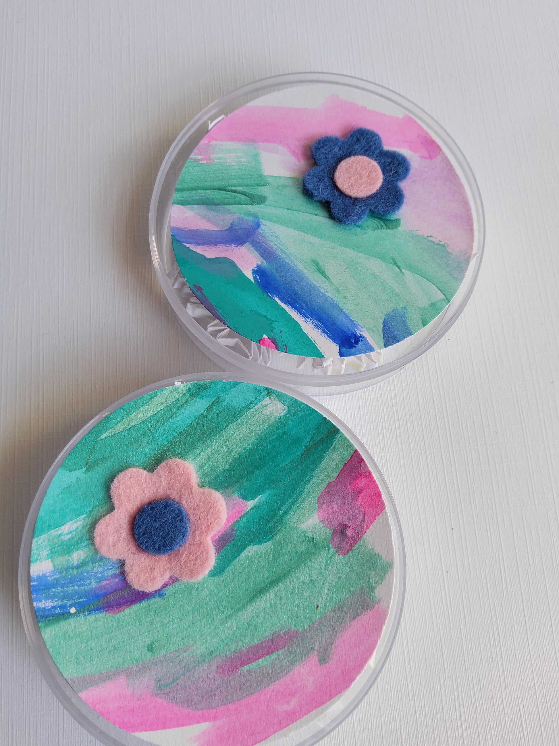 Two round containers with colorful floral designs on a white background
