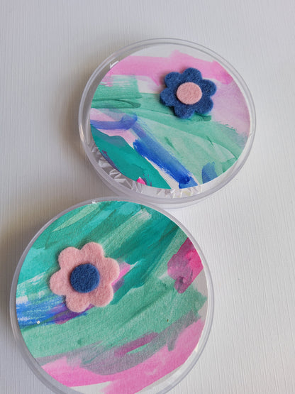 Two round containers with colorful floral designs on a white background
