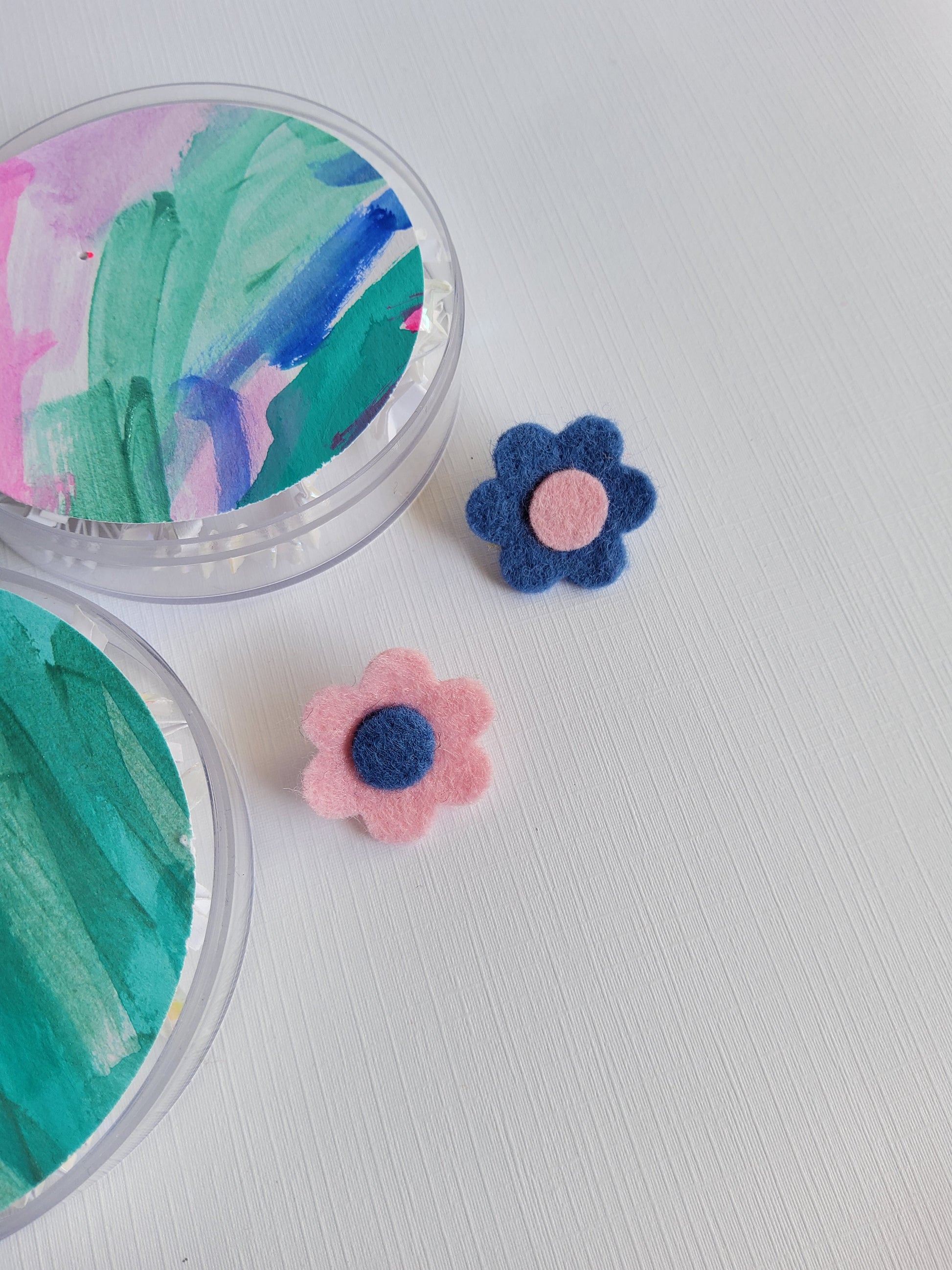 Two flower-shaped lapel pins on a white background