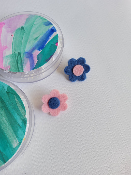 Two flower-shaped lapel pins on a white background