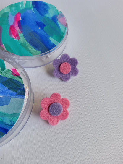 Colorful flower-shaped lapel pins on a textured white surface