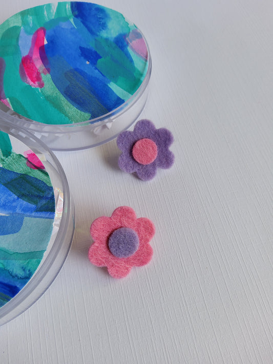 Colorful flower-shaped lapel pins on a textured white surface