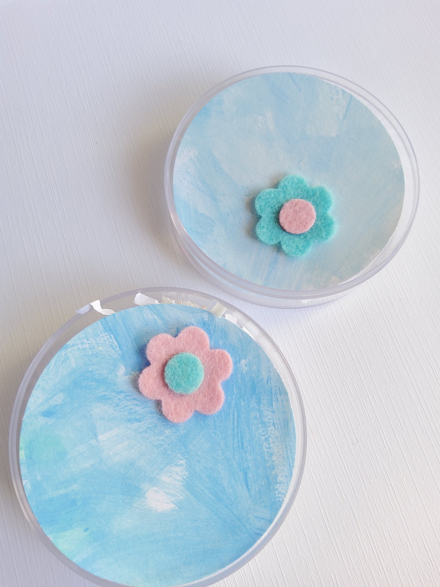 Two round containers with flower pins on a white background