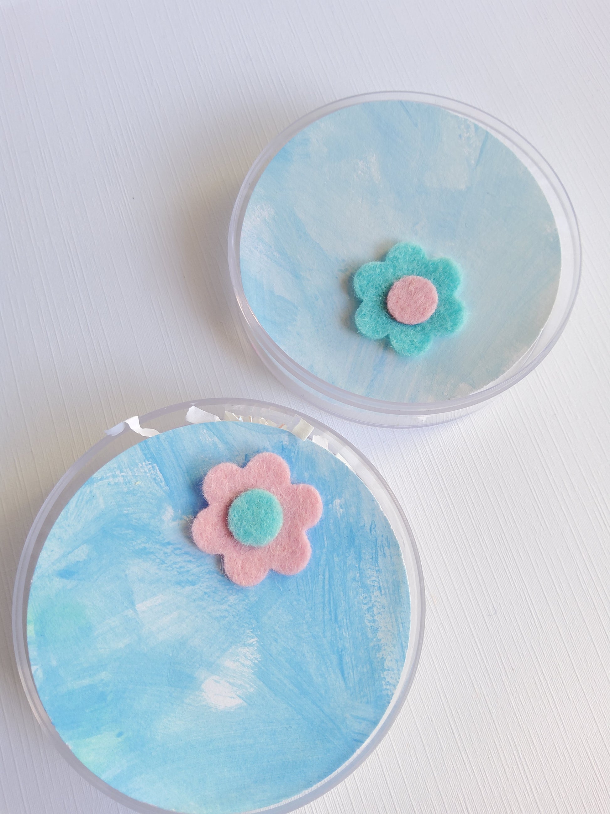 Two round containers with flower pins on a white background