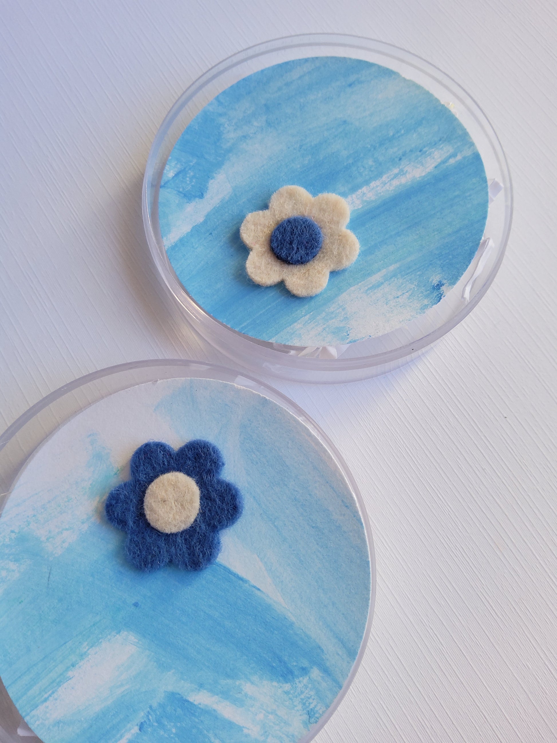 Two round containers with blue and white flower designs on a light background