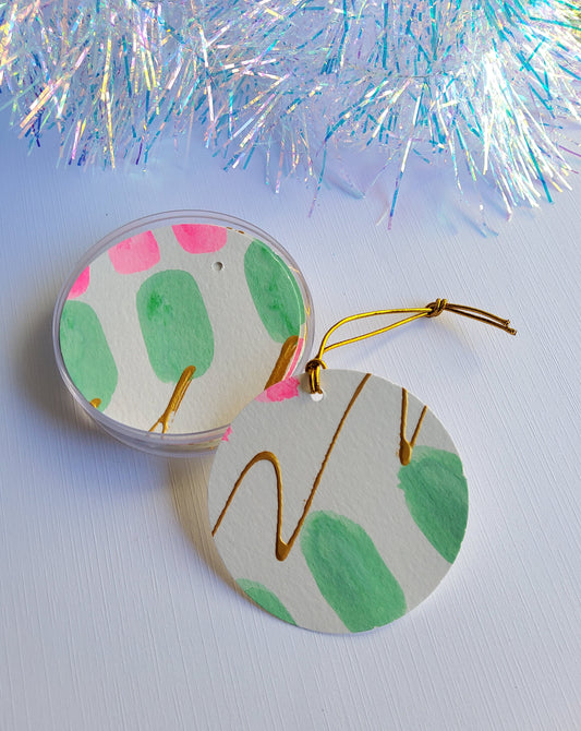 Pink, green and gold accented abstract hand-painted round gift tags with gold cords and iridescent tinsel background