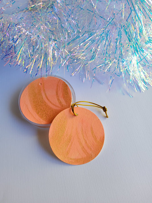 Gold and peachy coral abstract hand-painted round gift tags with gold cords and iridescent tinsel background