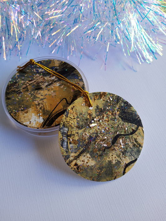 Black and gold glitter abstract hand-painted round gift tags with gold cords and iridescent tinsel background