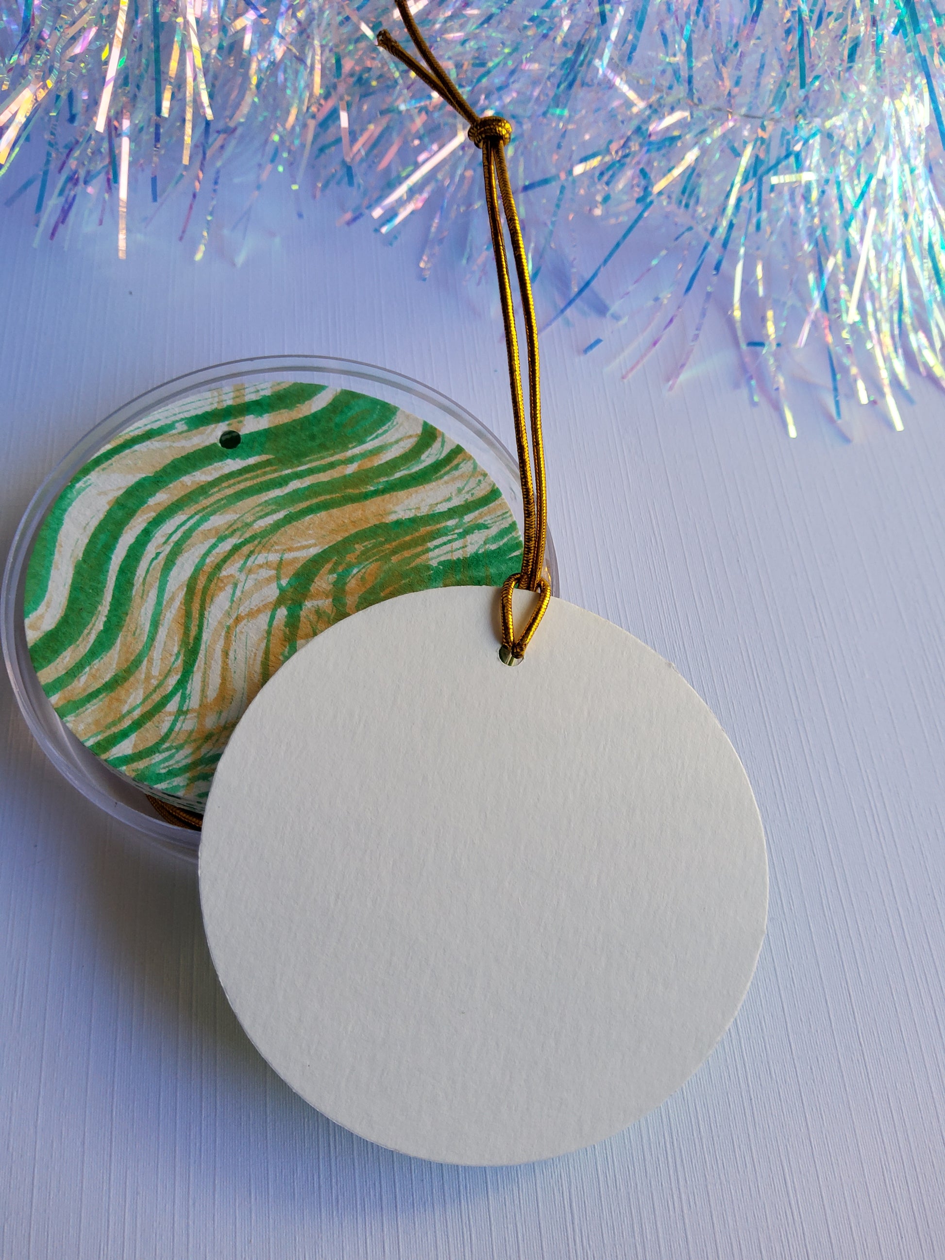 Green and gold  abstract hand-painted round gift tags with gold cords and iridescent tinsel background