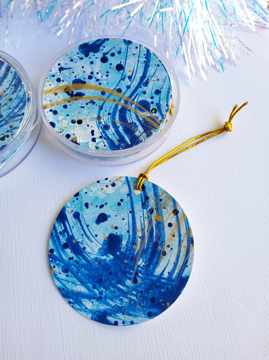 Blue and gold abstract hand-painted round gift tags with gold cords and iridescent tinsel background