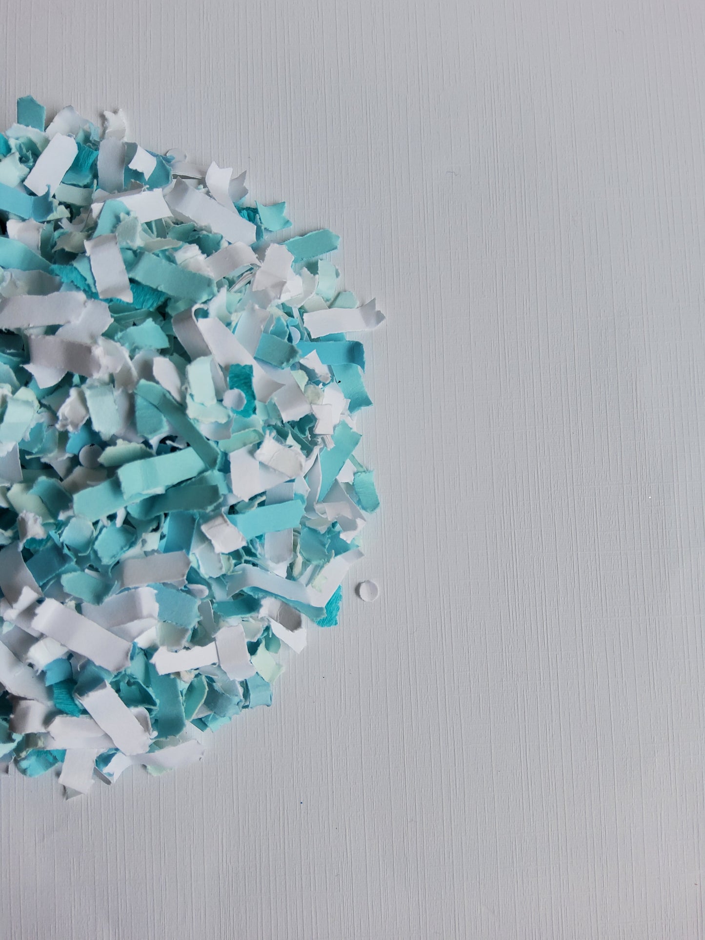 Turquoise and white paper confetti on a gray background