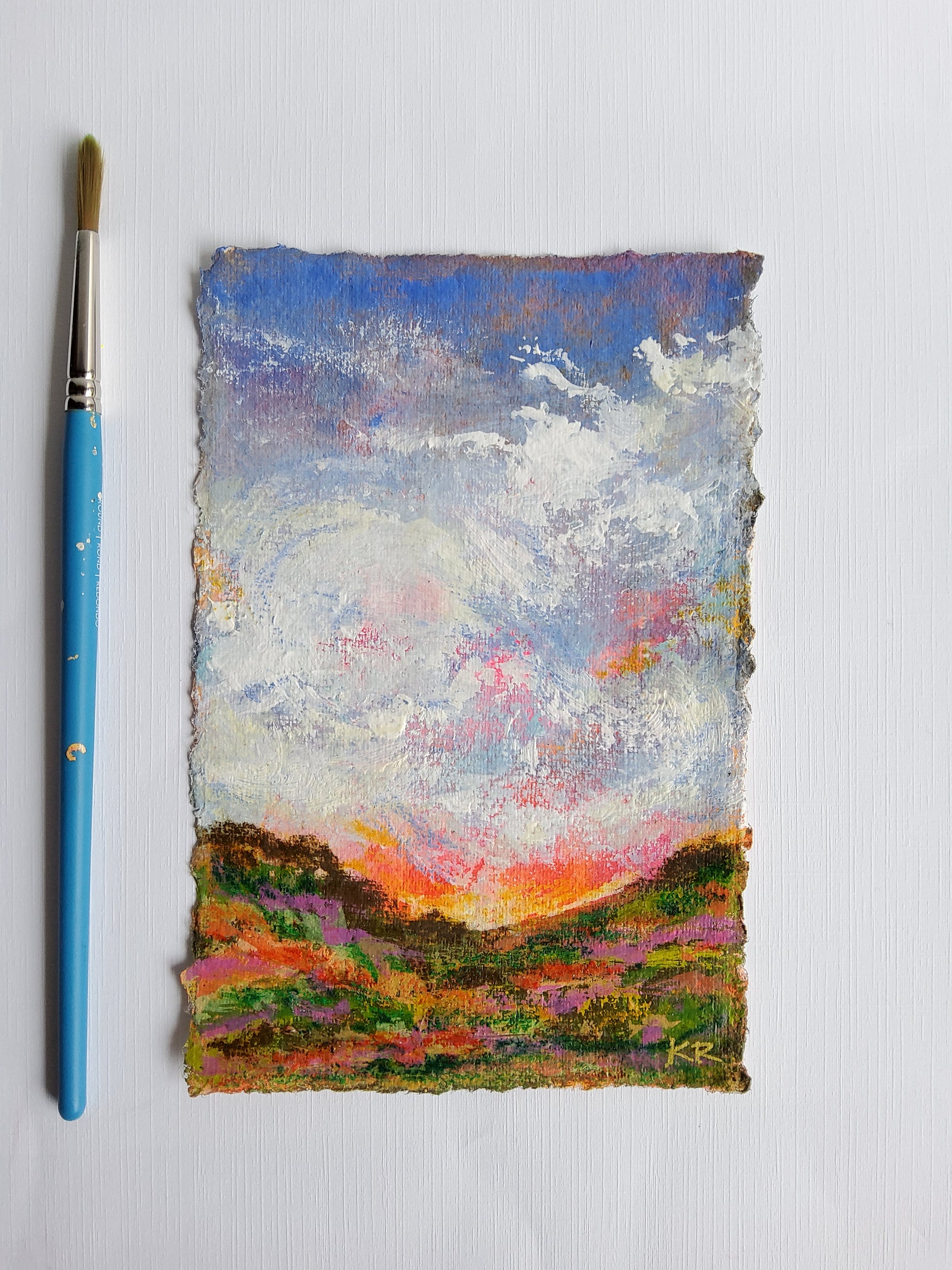 Abstract painting on a textured surface with a blue paintbrush below