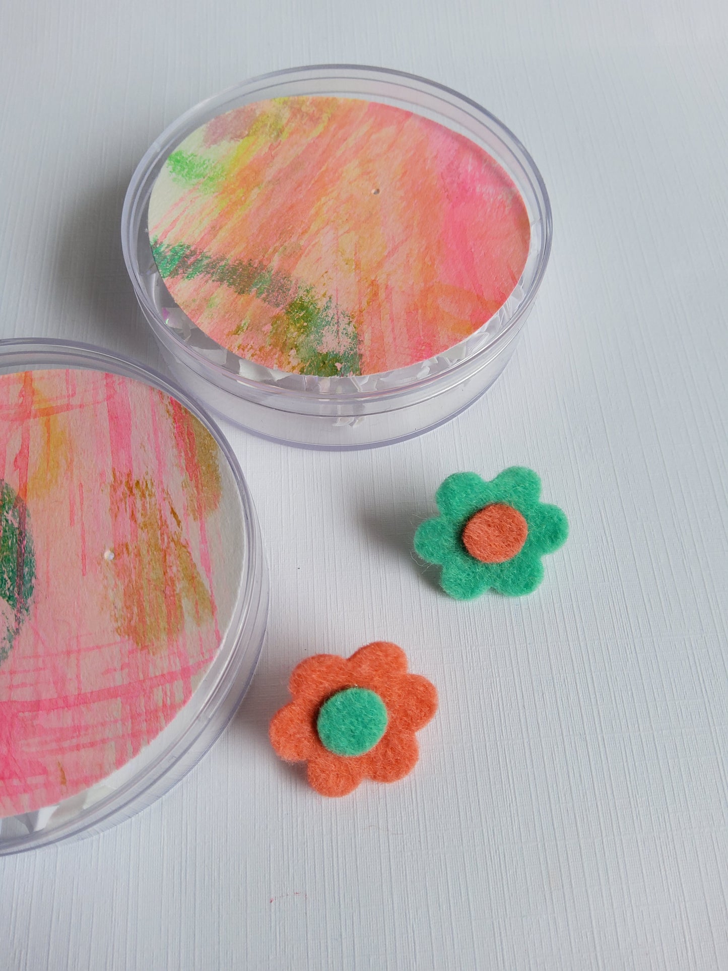 Two colorful flower-shaped felt lapel pins on a white surface