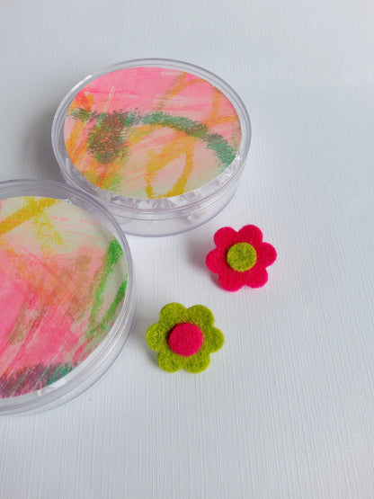 Two colorful felt flower pins with a pink and green design on a white background