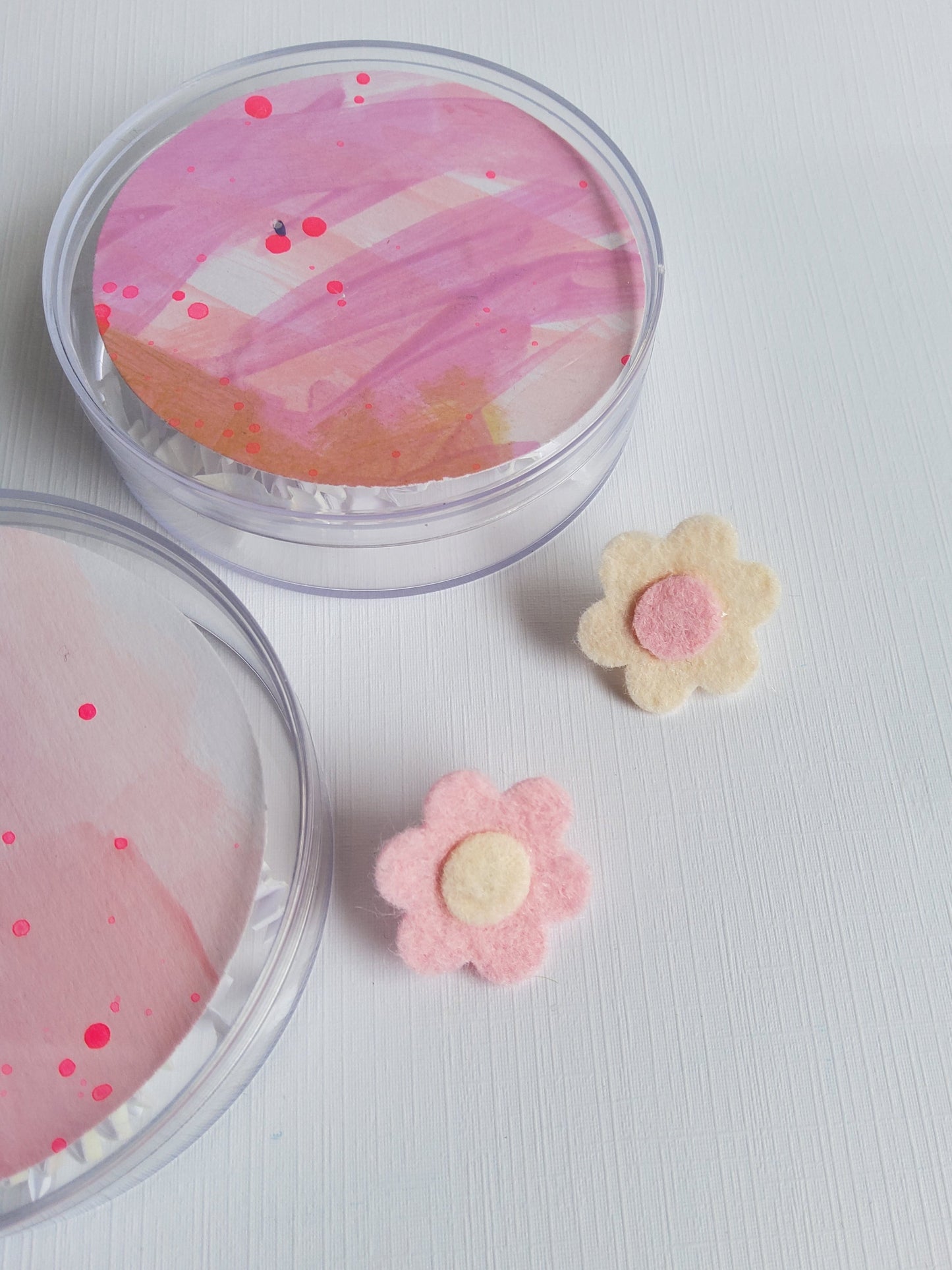 Two felt flower pins in pink and white on a white background 