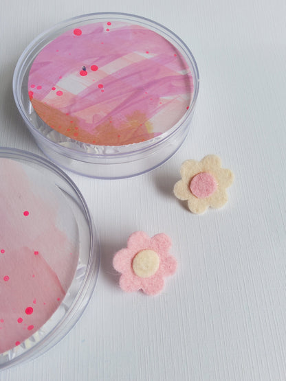 Two felt flower pins in pink and white on a white background 
