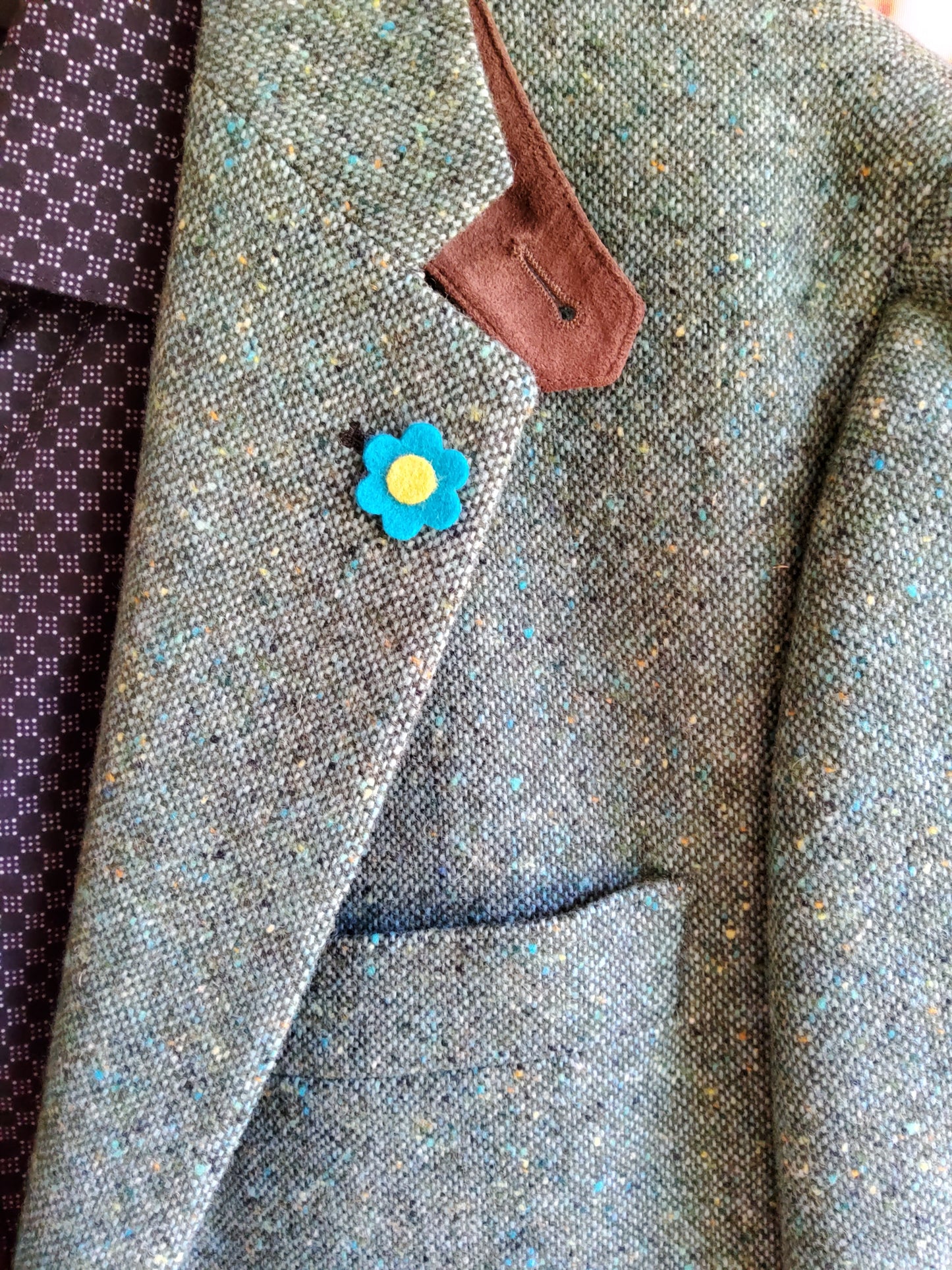 Close up of felt flower lapel pin on a blazer.