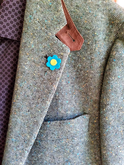 Close up of felt flower lapel pin on a blazer.